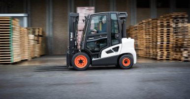 A black and white Bobcat Forklift moving pallets in an industrial warehouse setting.