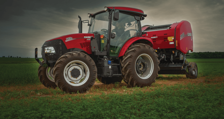 A Fully-serviced Red Case-IH Farmall Tractor Set In An Agricultural Field With A Slightly Blurred Background.