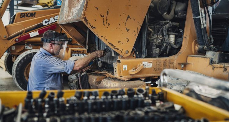 A member of ASCO Equipment’s service department performing planned maintenance on heavy equipment.