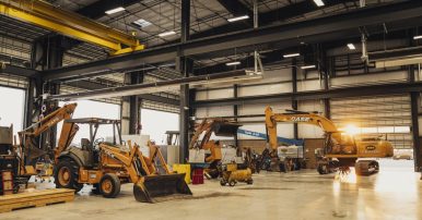 A small fleet of CASE construction machines sitting in a large warehouse awaiting planned maintenance.
