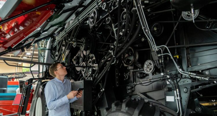 A parts & service professional at ASCO Equipment performing planned maintenance on a tractor.