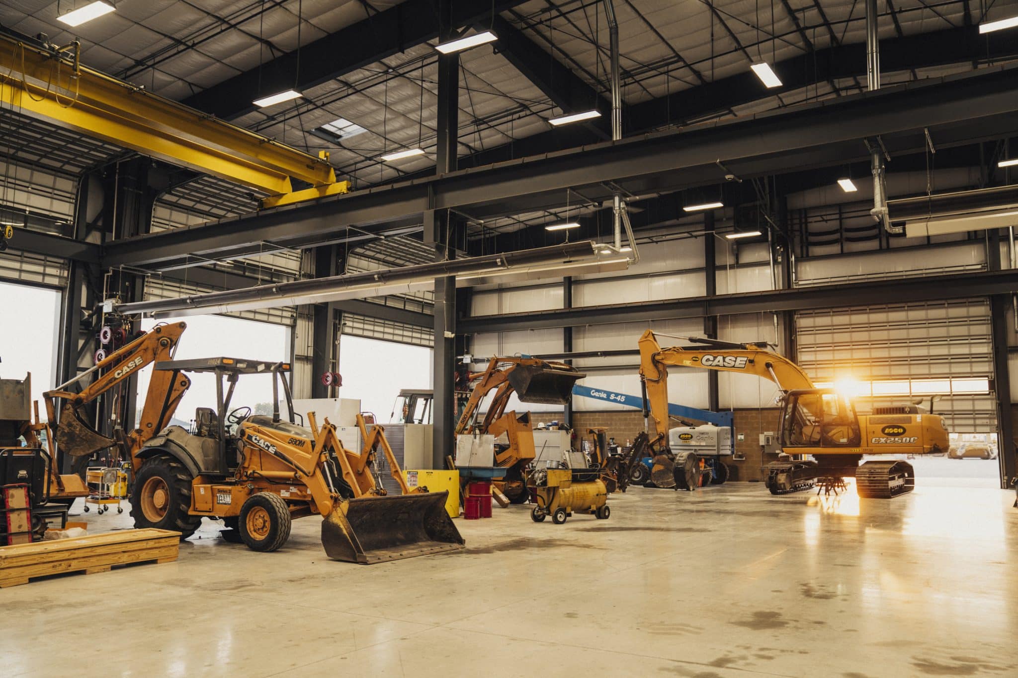 A small fleet of CASE construction machines sitting in a large warehouse awaiting planned maintenance.