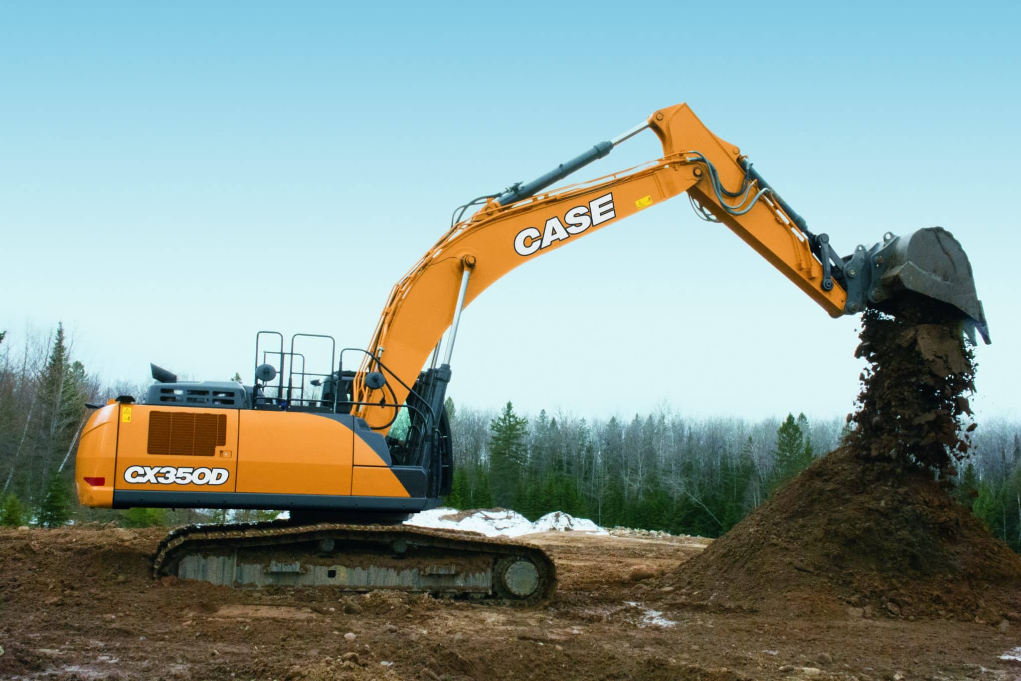 An orange Case excavator sitting on dirt at a construction site with an overcast sky background and trees in the background.