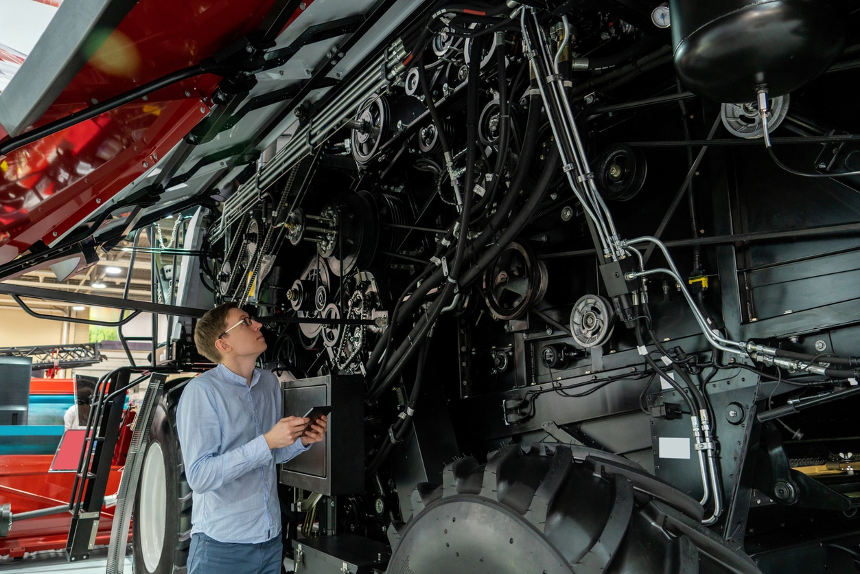 A parts & service professional at ASCO Equipment performing planned maintenance on a tractor.